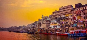 A riverside view with boats and buildings along the shore. - Shiv Kashi P Guest House By Glitz Hotels (Varanasi)