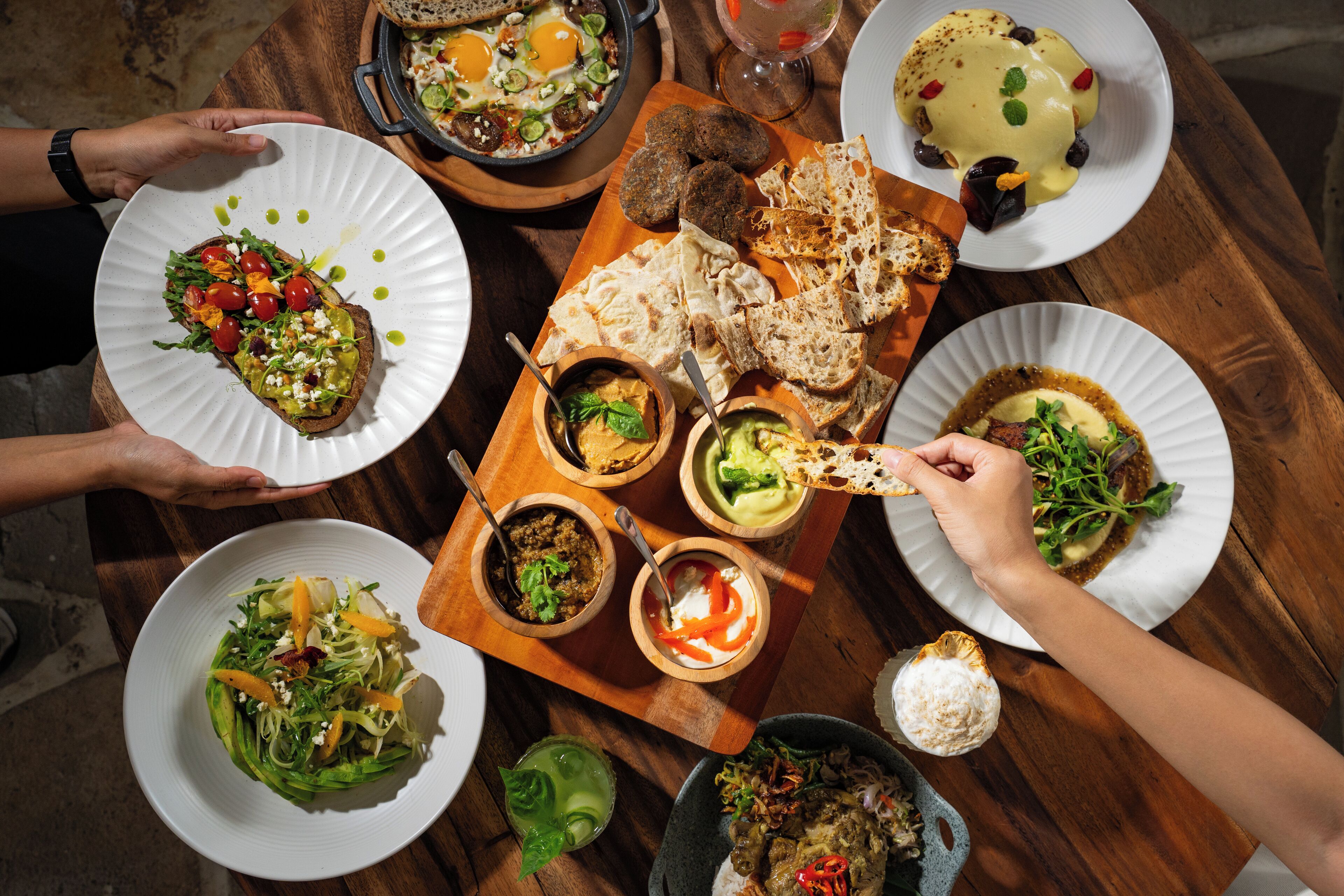 A wooden table with various dishes and bread.