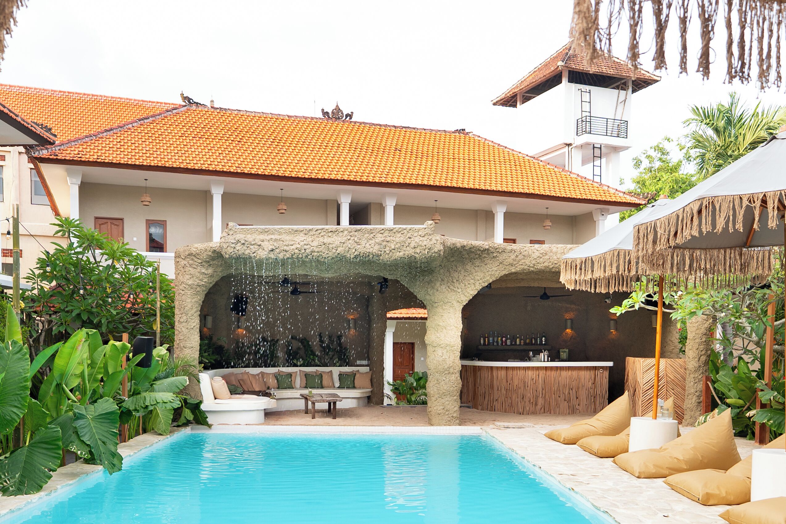 A pool area with a stone arch, lounge seating, and a bar.