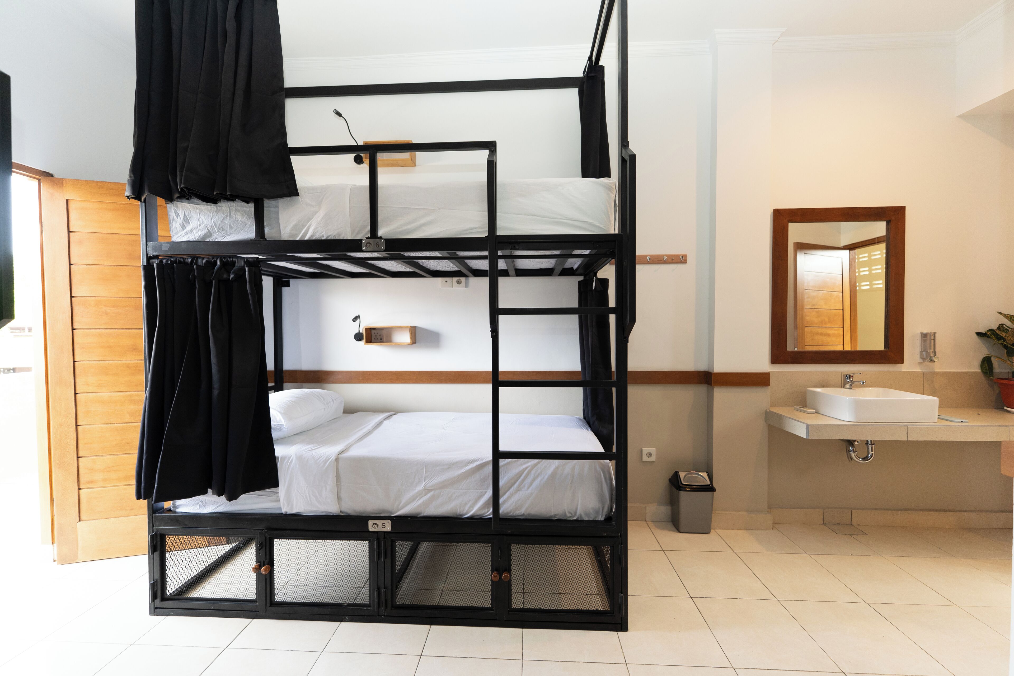 A bunk bed with a small shelf above it, a sink, and a mirror in a bathroom.
