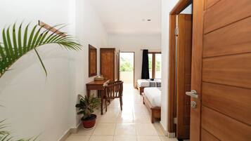 A hallway with a wooden door, a bed, a desk, and a chair.