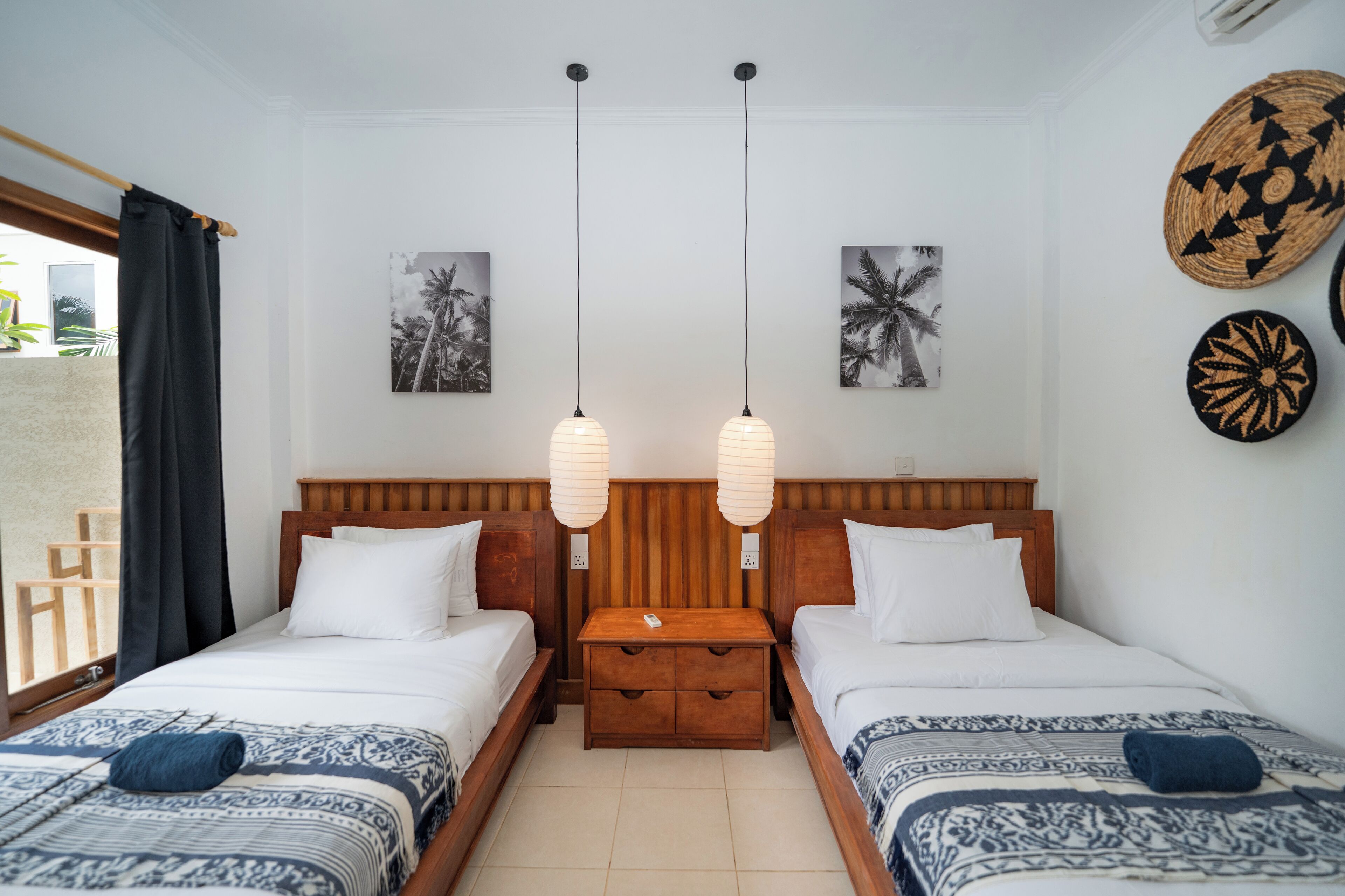 A hotel room with two beds, a wooden nightstand, and wall art.