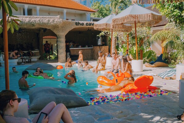 A pool area with inflatable floats, a bar, and a covered seating area. - Mad Monkey Uluwatu (Pecatu)
