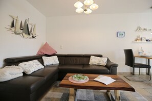 Ett modernt vardagsrum med en brun lädersoffa, ett träbord och en matplats med en stol och ett litet bord.