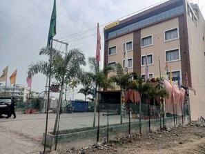 A multi-story building with a modern facade, a fenced outdoor area, and several flags.