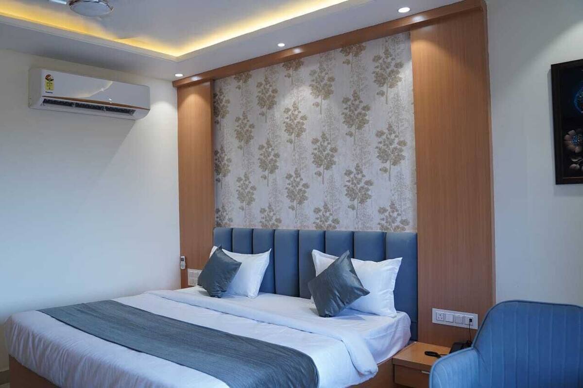 Een hotelkamer met een bed, nachtkastje, stoel en een airconditioner.
