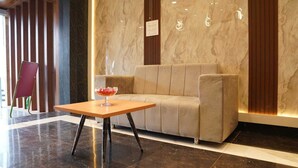 Un vestíbulo con un sofá, una mesa con un objeto de vidrio y una silla roja.