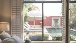 Ein Schlafzimmer mit großem Fenster und Blick auf einen Pool sowie eine Sitzgelegenheit im Freien.