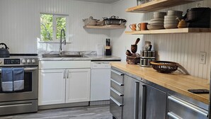 Una cocina moderna con armarios blancos, electrodomésticos de acero inoxidable y encimeras de madera.