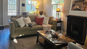 Una sala de estar acogedora con un sofá, sillones, una chimenea y una mesa de centro.