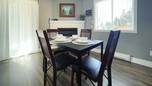 A dining room with a black table set for four, surrounded by wooden chairs.
