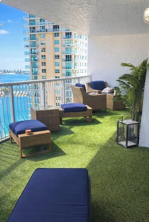 A balcony with wicker furniture, a small table, and a potted plant.