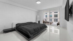 A modern bedroom with a large bed, a sliding glass door to a balcony, and a flat-screen TV mounted on the wall. - Luxury apartment in downtown Brickell with SEA view, Miami  (Miami)