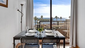 A dining area with a table set for four, overlooking a coastal view with palm trees and a clear sky. - Aloha Playa 402 - Terraze, Swimming Pool, Sea Views. Benalmadena (Benalmádena)
