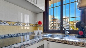 A kitchen with a granite countertop, a stainless steel sink, and a window with a view of buildings. - Aloha Playa 402 - Terraze, Swimming Pool, Sea Views. Benalmadena (Benalmádena)