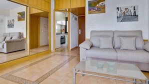 A living room with a sofa, a glass coffee table, and a kitchen in the background. - Aloha Playa 402 - Terraze, Swimming Pool, Sea Views. Benalmadena (Benalmádena)