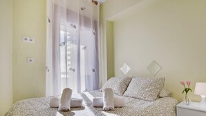 A bedroom with a bed, a nightstand, a vase with flowers, and a window with curtains. - Aloha Playa 402 - Terraze, Swimming Pool, Sea Views. Benalmadena (Benalmádena)