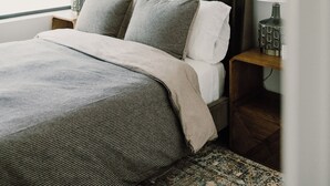A bedroom with a bed, two bedside tables, a nightstand, a window, and a ceiling fan. - Modern Townhome with Skyline Views, Heated Balcony & Curated Art in Downtown DSM (Des Moines)