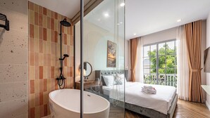 A modern bathroom with a freestanding bathtub, a glass shower enclosure, and a large window with curtains. - Venus Villa - Novaworld Phan Thiet (Tien Thanh)
