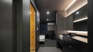 A modern hotel room with a wooden wardrobe, a bed, a desk, and a bathroom with a mirror and sink. - Anook Hotel Yeongdengpo (Seoul)