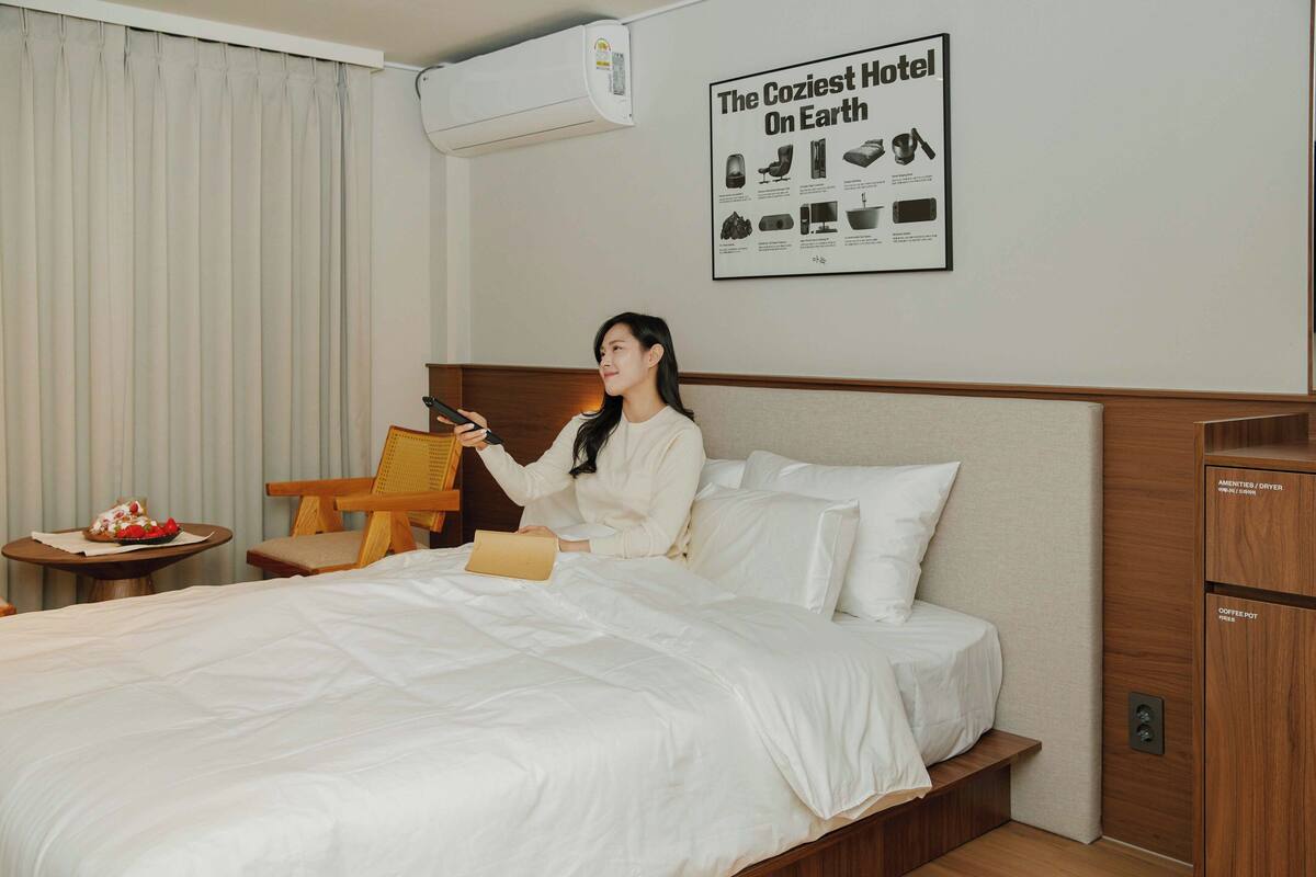Habitación de hotel con cama, una silla, una mesita con un plato de comida y un cartel en la pared.