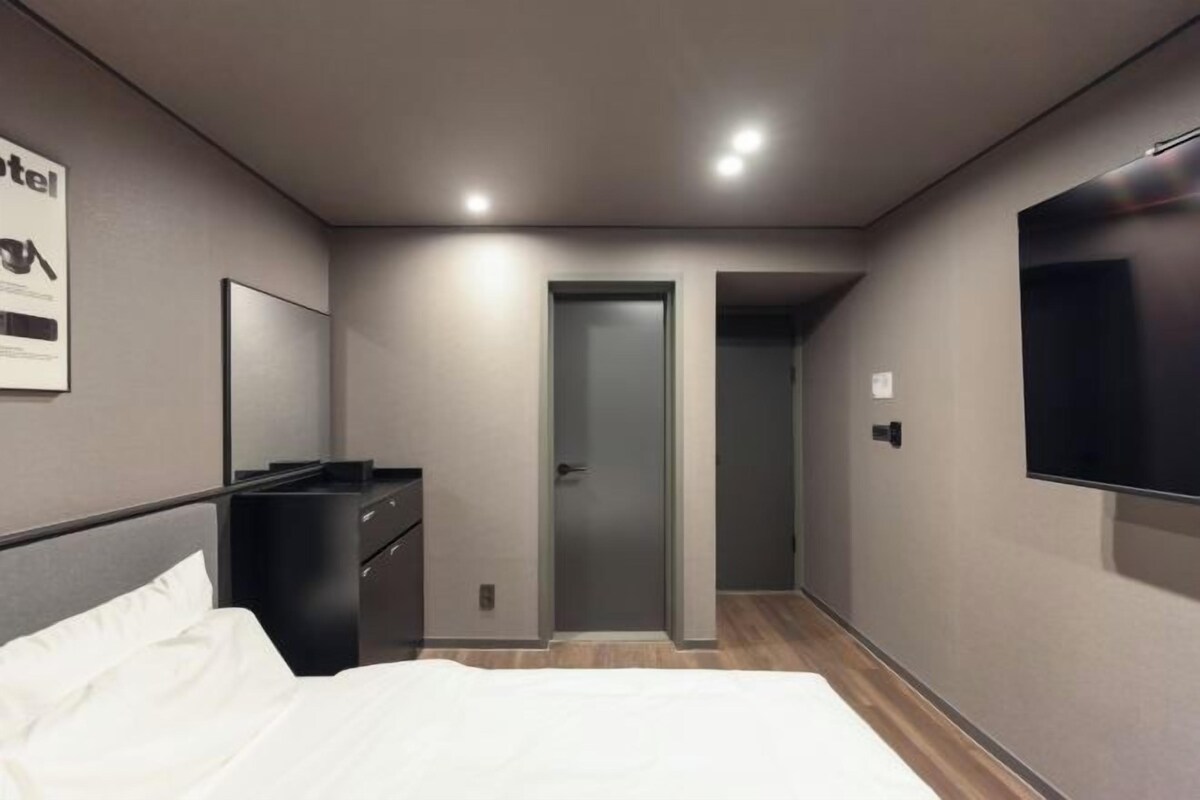 Una habitación de hotel moderna con una cama, un escritorio, un televisor y una puerta que da a otra habitación.