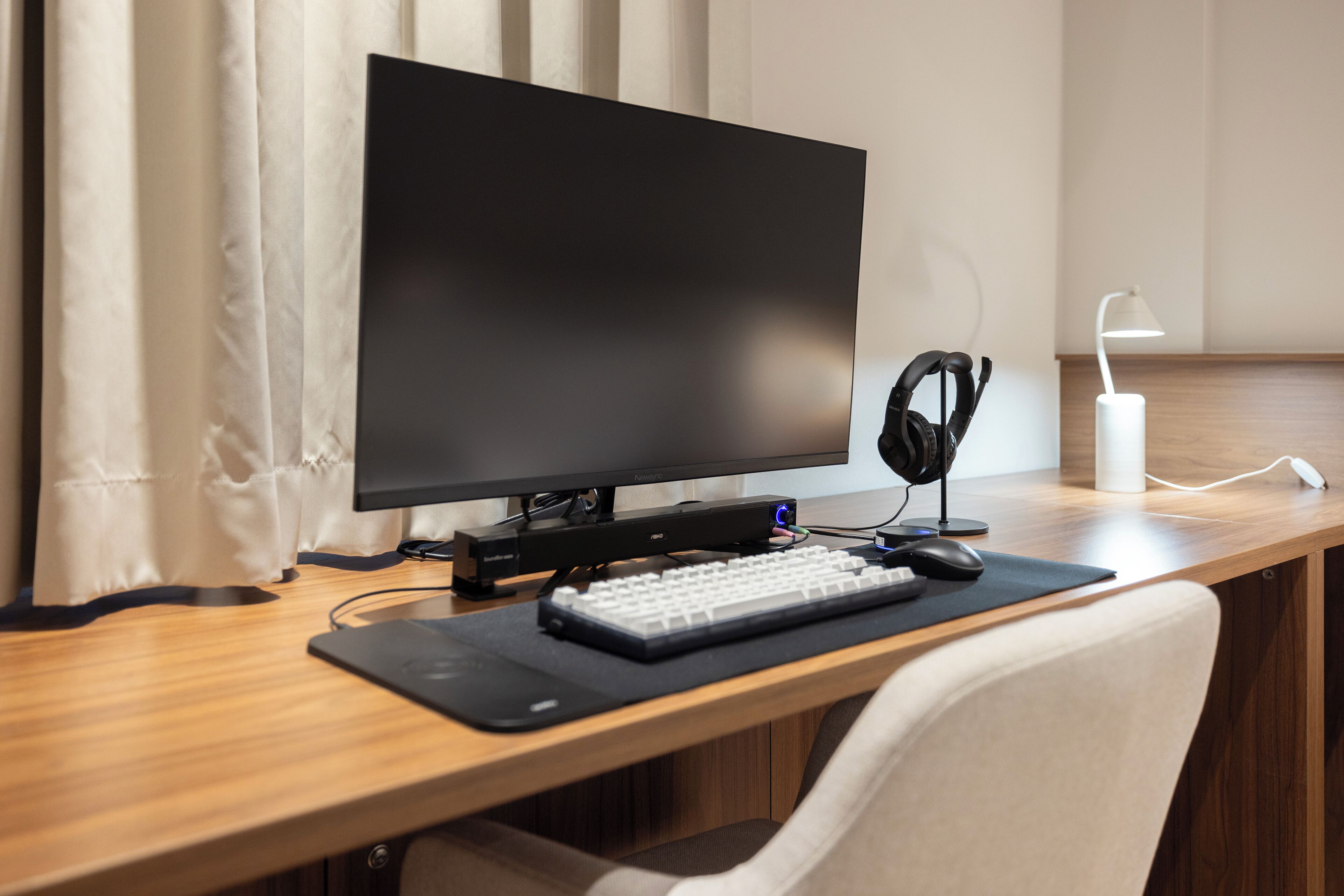 A wooden desk with a black monitor, keyboard, mouse, and headphones.
