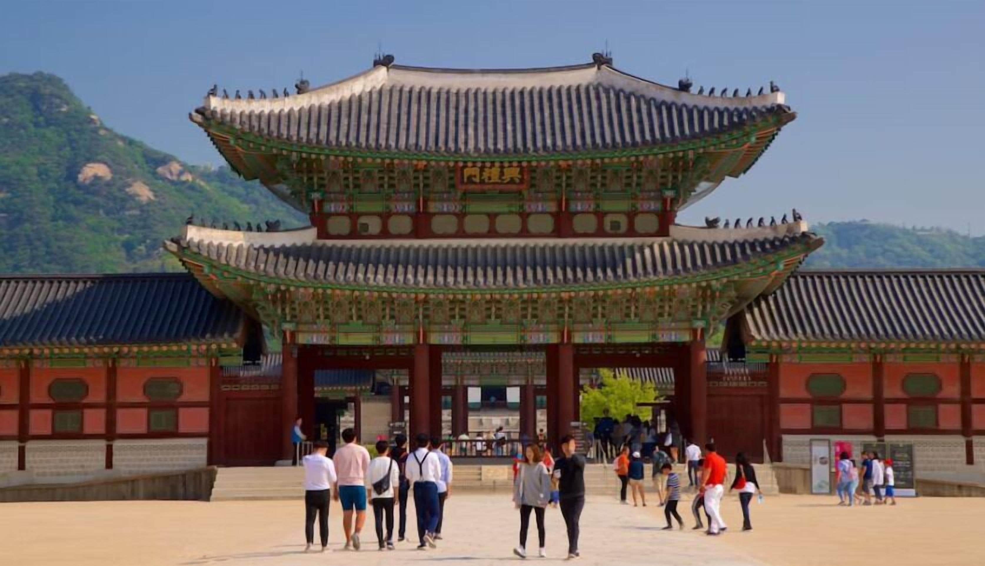 A traditional Korean gate with multiple tiers and ornate decorations, surrounded by visitors.