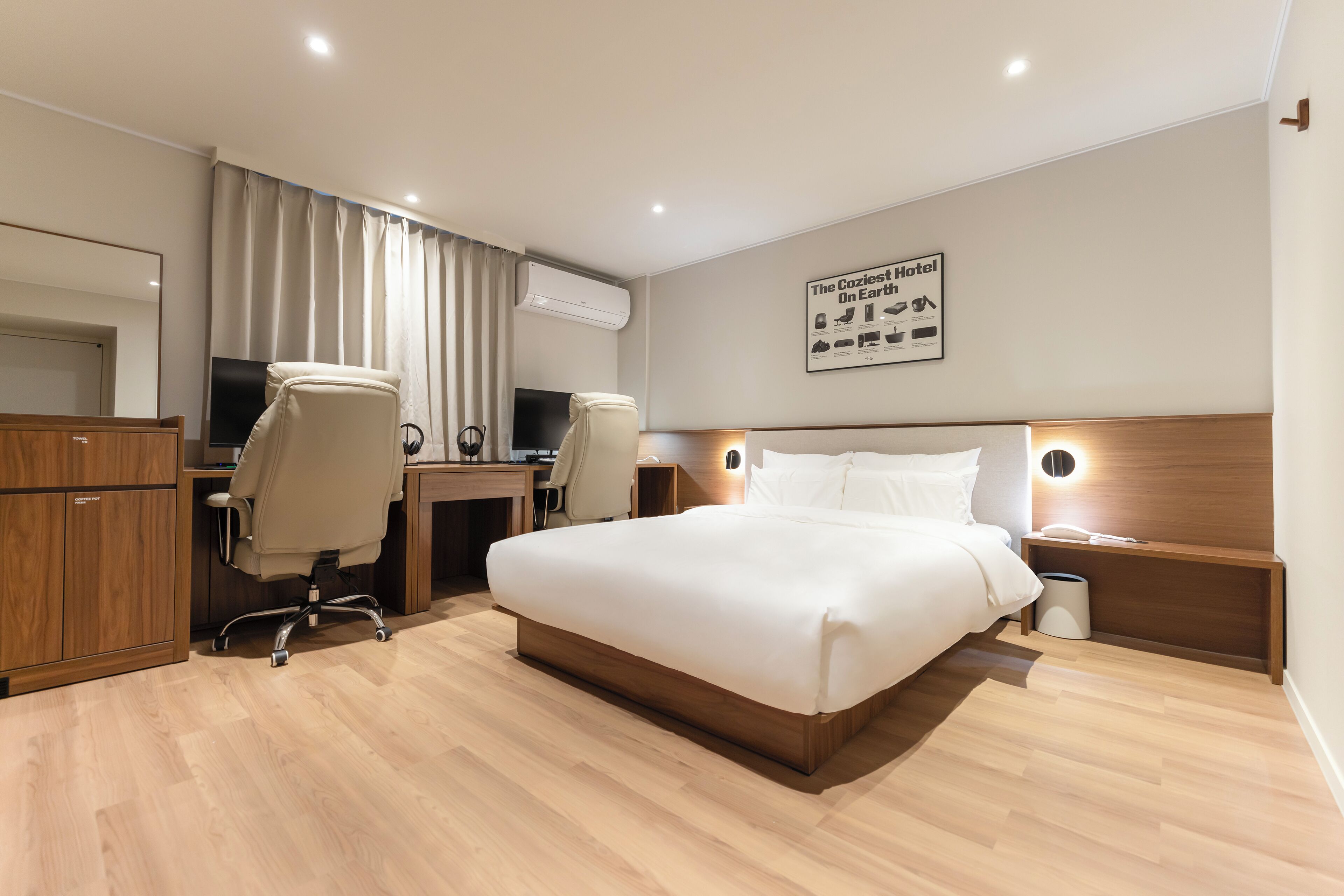 Une chambre d’hôtel moderne dotée d’un grand lit, d’un bureau avec deux chaises, d’une télévision et d’un climatiseur fixé au mur.