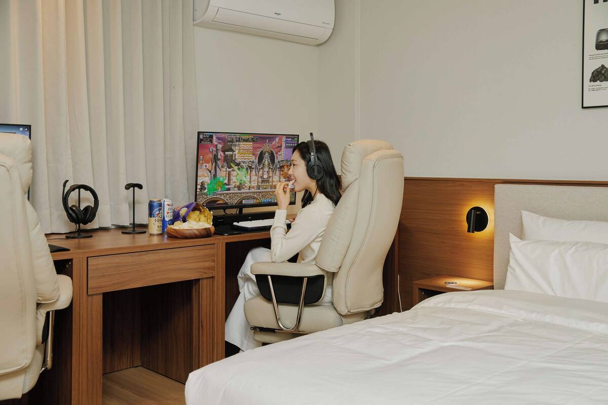 Una habitación de hotel con una cama, un escritorio con computadora y una silla.
