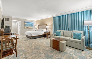 A hotel room with a bed, a sofa, a desk, and a lamp.
