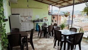 A kitchen with a refrigerator, stove, and cabinets. There is a dining area with a table and chairs. - hotel casa verde Guatapé (Guatapé)