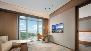 A modern hotel room with a large window, a sofa, a round table, and a cityscape view. - Guangzhou Tianwei Hotel  (Guangzhou)