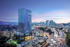 A modern high-rise building with a glass facade and a prominent logo, surrounded by a busy urban street with various vehicles and buildings. - Guangzhou Tianwei Hotel  (Guangzhou)