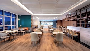 A modern restaurant with a central bar, wooden flooring, and a view of the city through large windows. - Guangzhou Tianwei Hotel  (Guangzhou)