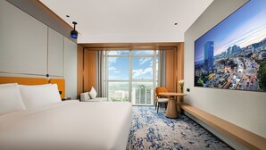 A hotel room with a large bed, a view of a cityscape, a small table with a vase, and a chair. - Guangzhou Tianwei Hotel  (Guangzhou)