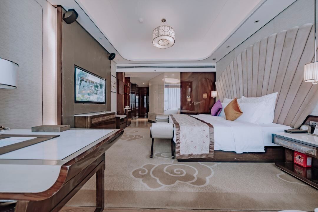 A modern hotel room with a large bed, a desk, and a television.