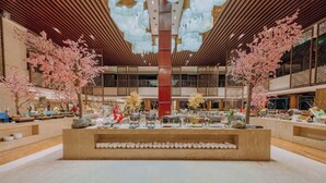 A spacious lobby with a central seating area, decorative trees, and a modern ceiling design.