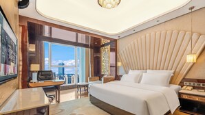 A modern hotel room with a large bed, a desk, and a view of the city.