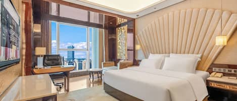 A modern hotel room with a large bed, a desk, and a view of the city.