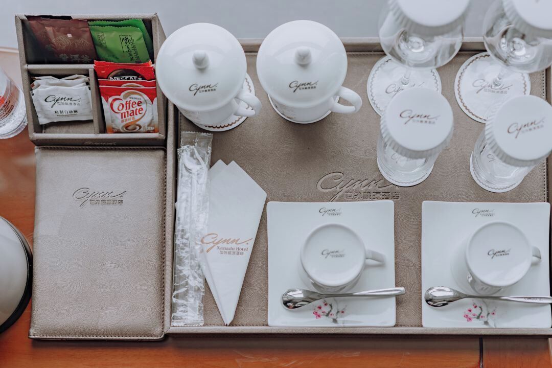 A tray with tea sets, coffee packets, and napkins labeled "Cynna Hotel."