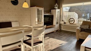 A cozy living room with a dining area, a television, and a window with a view.