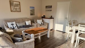 A living room with a sofa set, a wooden coffee table, and a dining area with chairs.