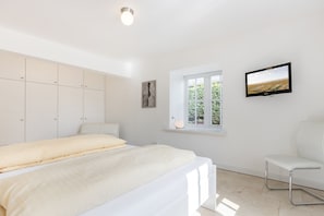 A bedroom with a bed, a chair, a TV, a window, and a wardrobe. - White Pearl ground floor - luxury apartment, close to the beach for 4 pers. with sauna, terrace, WLAN. (Westerland)