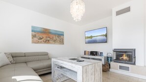 Ein modernes Wohnzimmer mit einer Eckcouch, einem Couchtisch, einem Flachbildfernseher, einem Kamin und Kunstwerken an den Wänden.