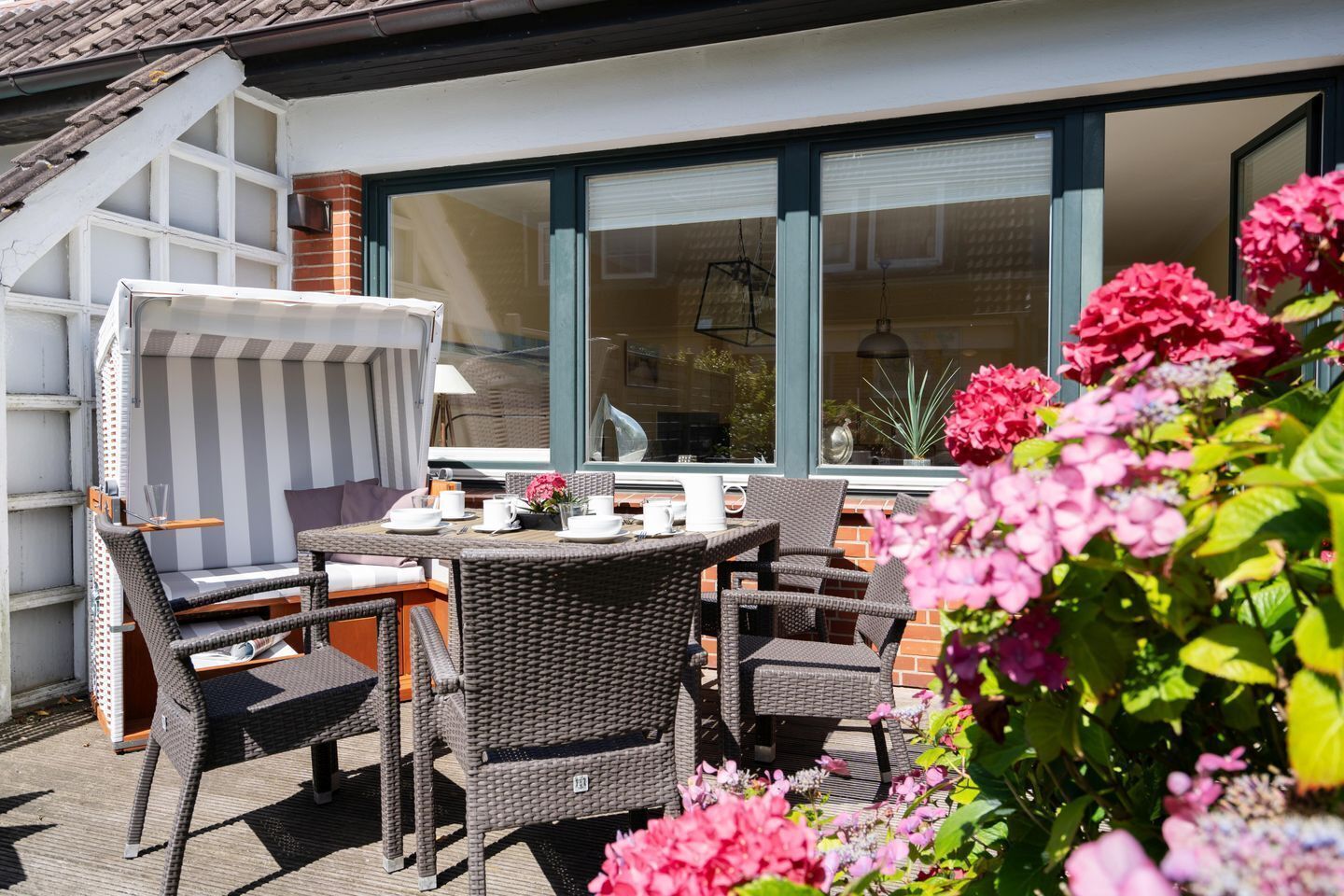 An outdoor patio with wicker furniture, a table set for two, and a window with blinds.
