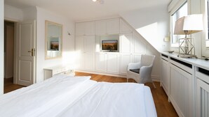 A bedroom with a bed, a chair, a TV, and a desk with a lamp. - Meeresstern - Beautiful house for 6 pers. with terrace, parking space, WLAN. (Westerland)