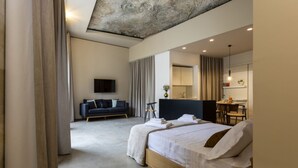 A modern hotel room with a large bed, a sofa, a dining area, and a TV. - Villa with heated pool located in a unique position (Modica)