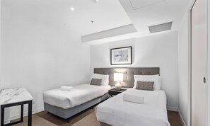 Une chambre d’hôtel avec deux lits, une table de chevet avec une lampe, un tableau encadré au mur et une table en marbre.