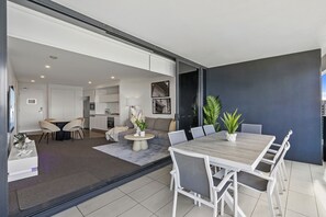 A modern living space with a dining area, kitchen, and a large sliding glass door leading to an outdoor area.